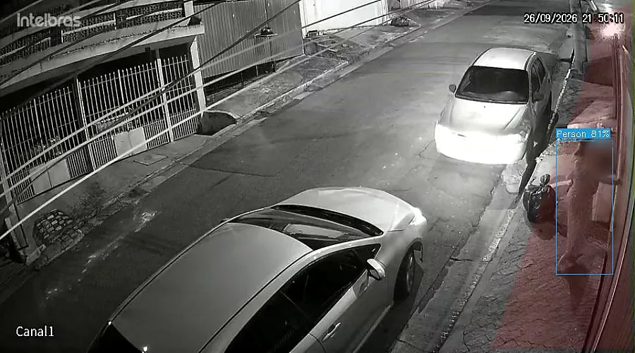 Imagem real noturna de câmera em uma rua residencial: a inteligência artificial marca a pessoa que chega junto ao portão. Rosto desfocado.